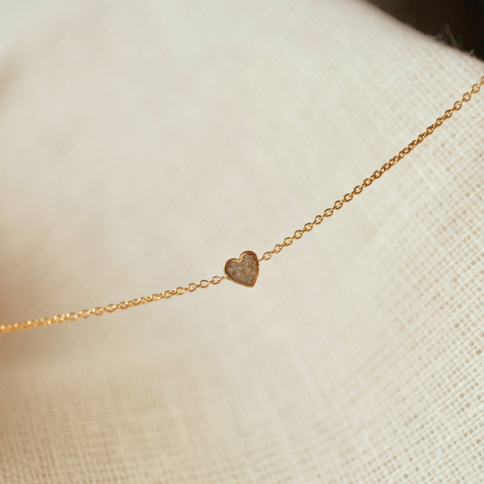 Gouden Minitials armband met ashanger op een wit doek